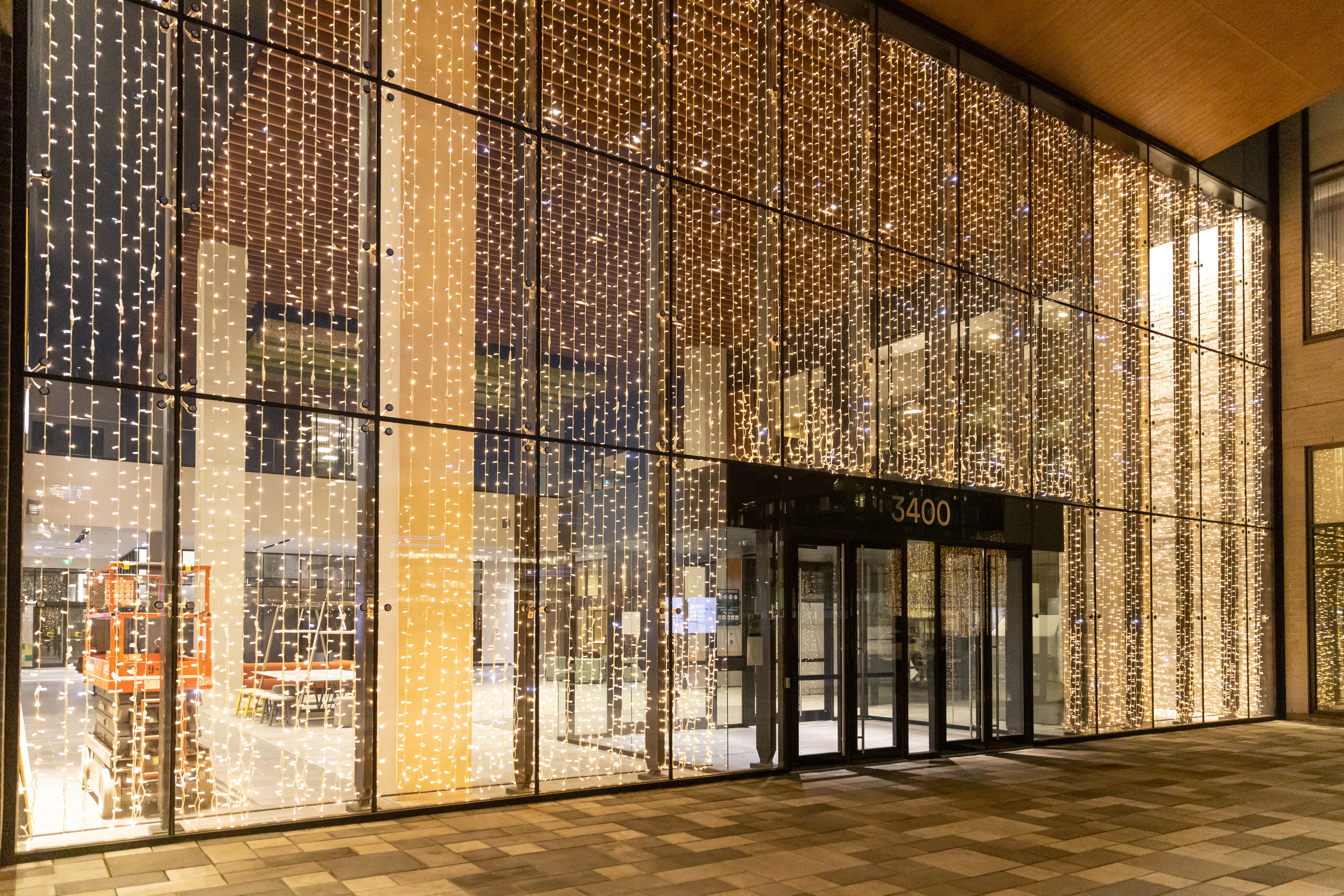 Festive lighting design for businesses – modern corporate campus Christmas lighting with gold and white light elements on office buildings by MK Illumination.