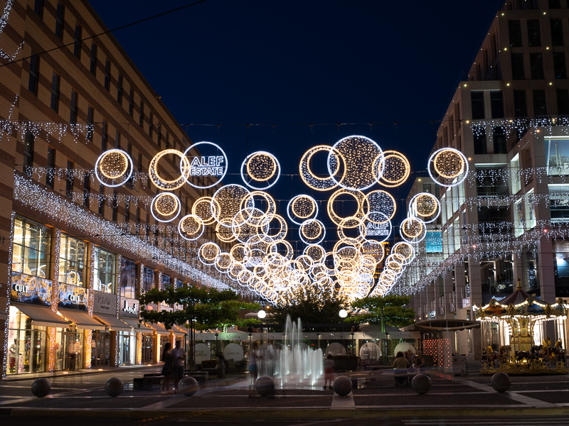 Across-street lighting motifs in a city center – MK Illumination, designed for safety and atmosphere.